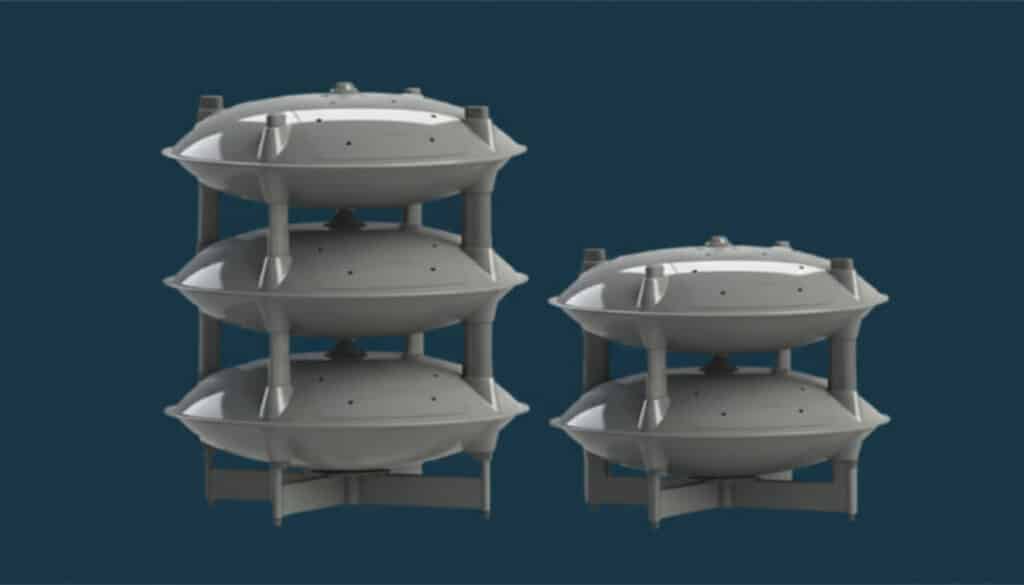 A digital rendering of three stacks of gray, circular, multi-story structures resembling futuristic outdoor warning system buildings, set against a plain dark blue background. The left stack is the tallest with 3 units, and the other has 2